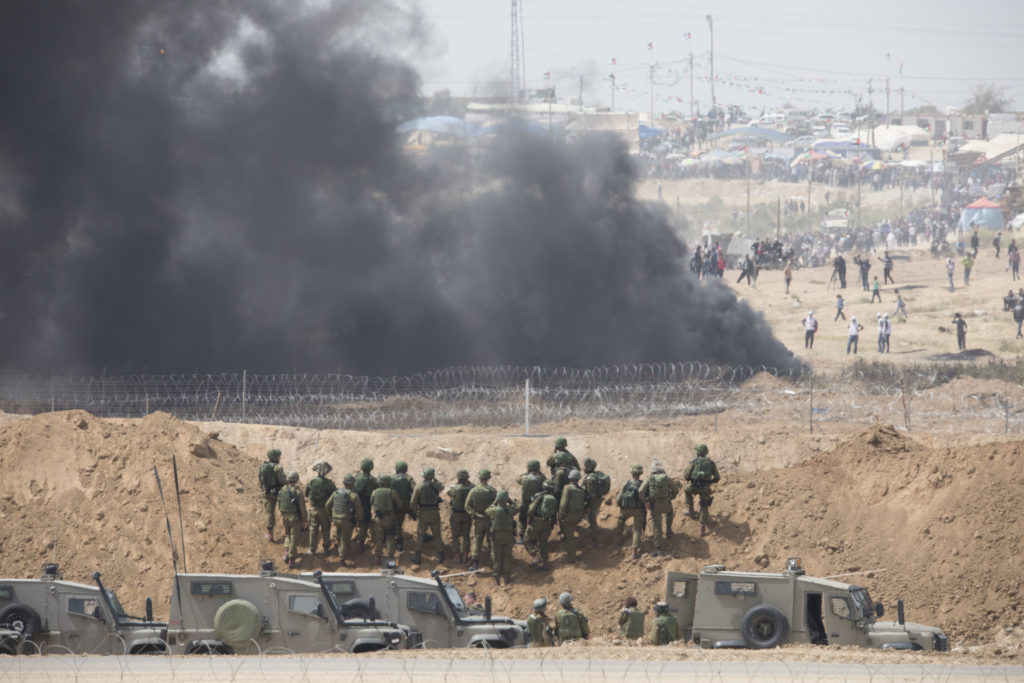 Tirs de gaz lacrymogène et à balles réelles de l'armée israélienne durant une manifestation sur la "ligne verte". Les palestinien·nes tentent d'échapper à la vue des soldat·es israélien·nes en brûlant des pneus. La photo est prise depuis le kibbutz de Nahal Oz, dans le sud d'Israël • 13 avril 2018 • Oren Ziv / Activestills.org
